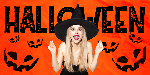 Image showing Young woman in hat as a witch on scary red background