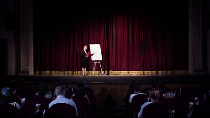 Image showing Female caucasian speaker giving presentation in hall at university or business centre workshop