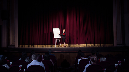 Image showing Female caucasian speaker giving presentation in hall at university or business centre workshop