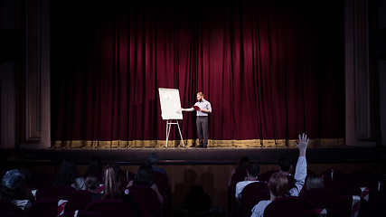 Image showing Male caucasian speaker giving presentation in hall at university or business centre workshop