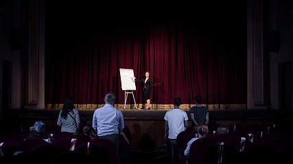 Image showing Female caucasian speaker giving presentation in hall at university or business centre workshop