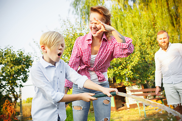 Image showing Happy family during watering plants in a garden outdoors. Love, family, lifestyle, harvest concept.