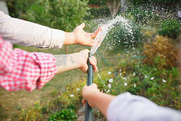 Image showing Happy family during watering plants in a garden outdoors. Love, family, lifestyle, harvest concept.