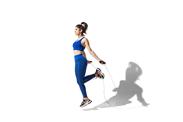 Image showing Beautiful young female athlete practicing on white studio background with shadows