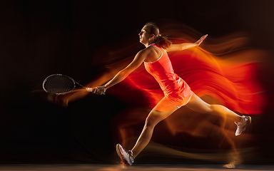 Image showing Professional female tennis player isolated on black studio background in mixed light