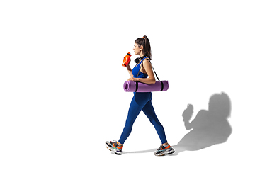 Image showing Beautiful young female athlete practicing on white studio background with shadows