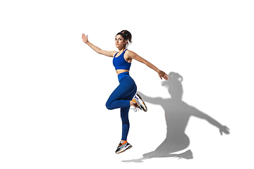 Image showing Beautiful young female athlete practicing on white studio background with shadows