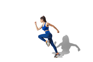 Image showing Beautiful young female athlete practicing on white studio background with shadows