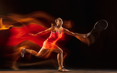 Image showing Professional female tennis player isolated on black studio background in mixed light