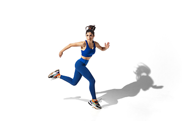 Image showing Beautiful young female athlete practicing on white studio background with shadows