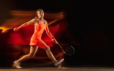 Image showing Professional female tennis player isolated on black studio background in mixed light