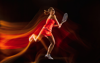 Image showing Professional female tennis player isolated on black studio background in mixed light