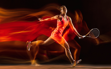 Image showing Professional female tennis player isolated on black studio background in mixed light