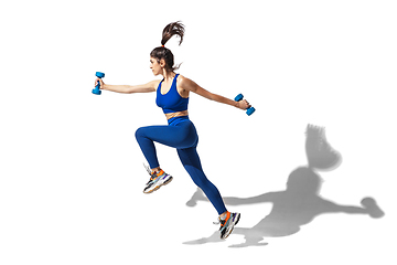 Image showing Beautiful young female athlete practicing on white studio background with shadows