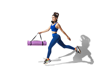 Image showing Beautiful young female athlete practicing on white studio background with shadows