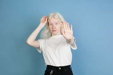 Image showing Portrait of beautiful caucasian albino girl isolated on blue studio background