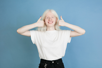 Image showing Portrait of beautiful caucasian albino girl isolated on blue studio background