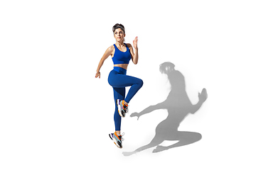 Image showing Beautiful young female athlete practicing on white studio background with shadows