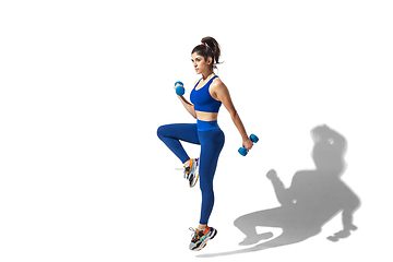 Image showing Beautiful young female athlete practicing on white studio background with shadows