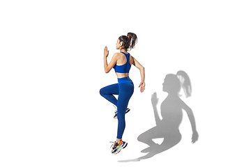 Image showing Beautiful young female athlete practicing on white studio background with shadows