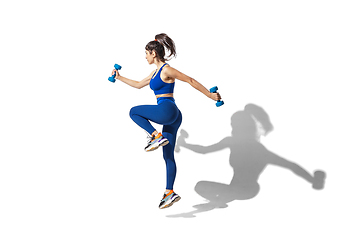 Image showing Beautiful young female athlete practicing on white studio background with shadows