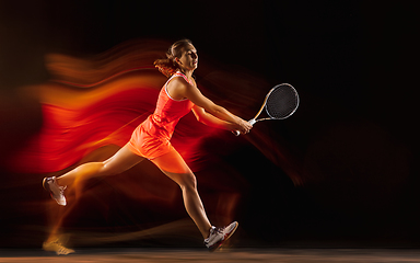 Image showing Professional female tennis player isolated on black studio background in mixed light