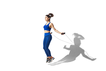 Image showing Beautiful young female athlete practicing on white studio background with shadows