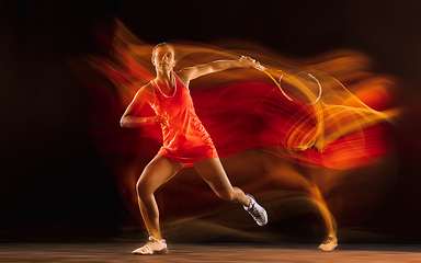 Image showing Professional female tennis player isolated on black studio background in mixed light