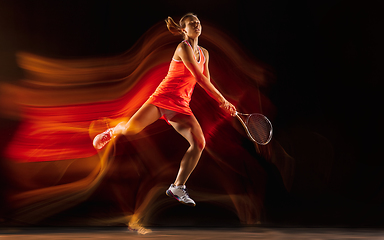 Image showing Professional female tennis player isolated on black studio background in mixed light