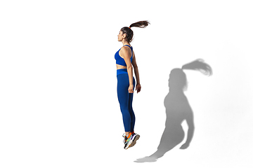 Image showing Beautiful young female athlete practicing on white studio background with shadows