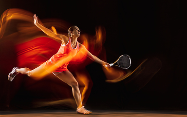 Image showing Professional female tennis player isolated on black studio background in mixed light