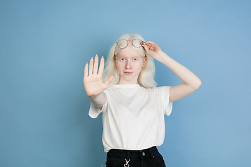 Image showing Portrait of beautiful caucasian albino girl isolated on blue studio background