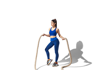 Image showing Beautiful young female athlete practicing on white studio background with shadows