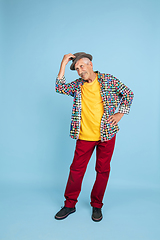 Image showing Senior hipster man in stylish hat isolated on blue background. Tech and joyful elderly lifestyle concept