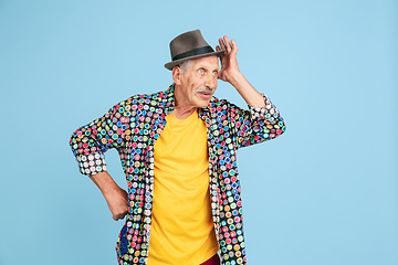 Image showing Senior hipster man in stylish hat isolated on blue background. Tech and joyful elderly lifestyle concept