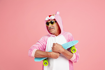 Image showing Senior hipster man in stylish pink attire isolated on pink background. Tech and joyful elderly lifestyle concept