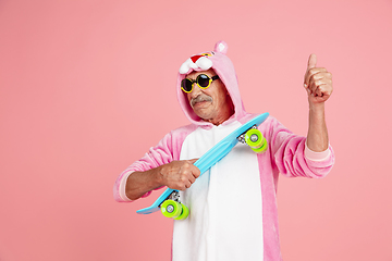 Image showing Senior hipster man in stylish pink attire isolated on pink background. Tech and joyful elderly lifestyle concept