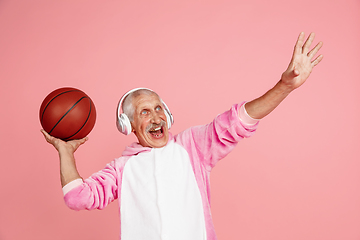 Image showing Senior hipster man in stylish pink attire isolated on pink background. Tech and joyful elderly lifestyle concept