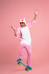 Image showing Senior hipster man in stylish pink attire isolated on pink background. Tech and joyful elderly lifestyle concept