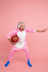 Image showing Senior hipster man in stylish pink attire isolated on pink background. Tech and joyful elderly lifestyle concept