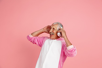 Image showing Senior hipster man in stylish pink attire isolated on pink background. Tech and joyful elderly lifestyle concept