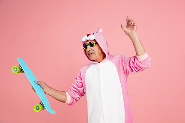 Image showing Senior hipster man in stylish pink attire isolated on pink background. Tech and joyful elderly lifestyle concept