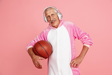 Image showing Senior hipster man in stylish pink attire isolated on pink background. Tech and joyful elderly lifestyle concept