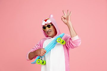 Image showing Senior hipster man in stylish pink attire isolated on pink background. Tech and joyful elderly lifestyle concept