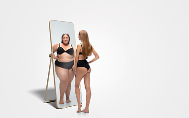 Image showing Young slim woman looking at fat girl in mirror\'s reflection on white background