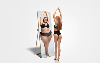 Image showing Young slim woman looking at fat girl in mirror\'s reflection on white background