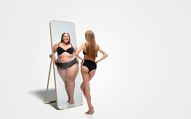 Image showing Young slim woman looking at fat girl in mirror\'s reflection on white background