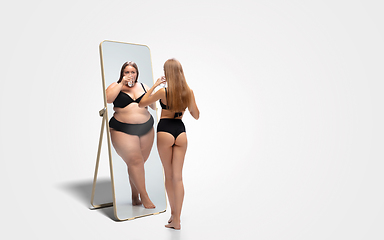 Image showing Young slim woman looking at fat girl in mirror\'s reflection on white background