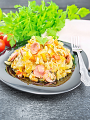 Image showing Cabbage stew with sausages in black plate on dark board