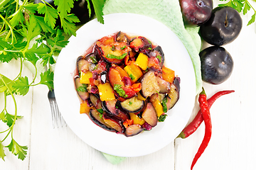 Image showing Eggplant with plums in plate on board top